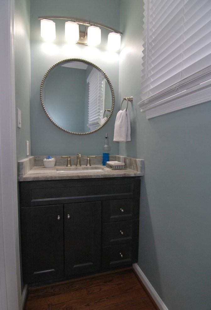 Bild på ett litet vintage grå grått toalett, med skåp i shakerstil, grå skåp, blå väggar, mellanmörkt trägolv, ett undermonterad handfat, granitbänkskiva och brunt golv