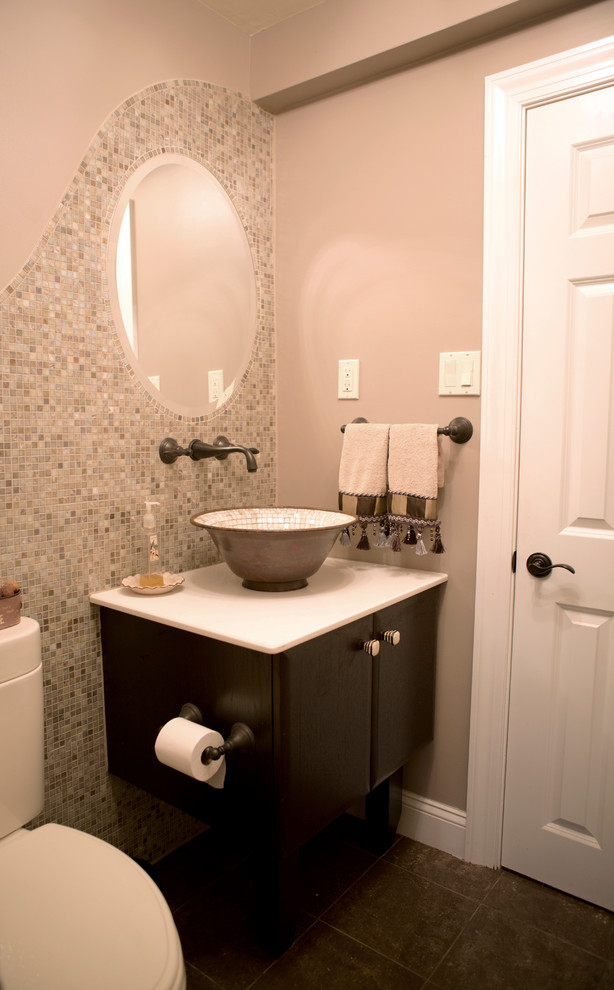 Example of a mid-sized trendy mosaic tile ceramic tile powder room design in Philadelphia with flat-panel cabinets, dark wood cabinets, a one-piece toilet, beige walls, a vessel sink and solid surface countertops