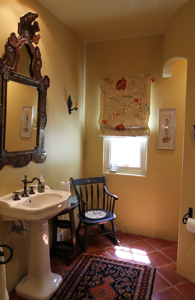 Mid-sized tuscan terra-cotta tile powder room photo in Phoenix with a pedestal sink, a one-piece toilet and yellow walls