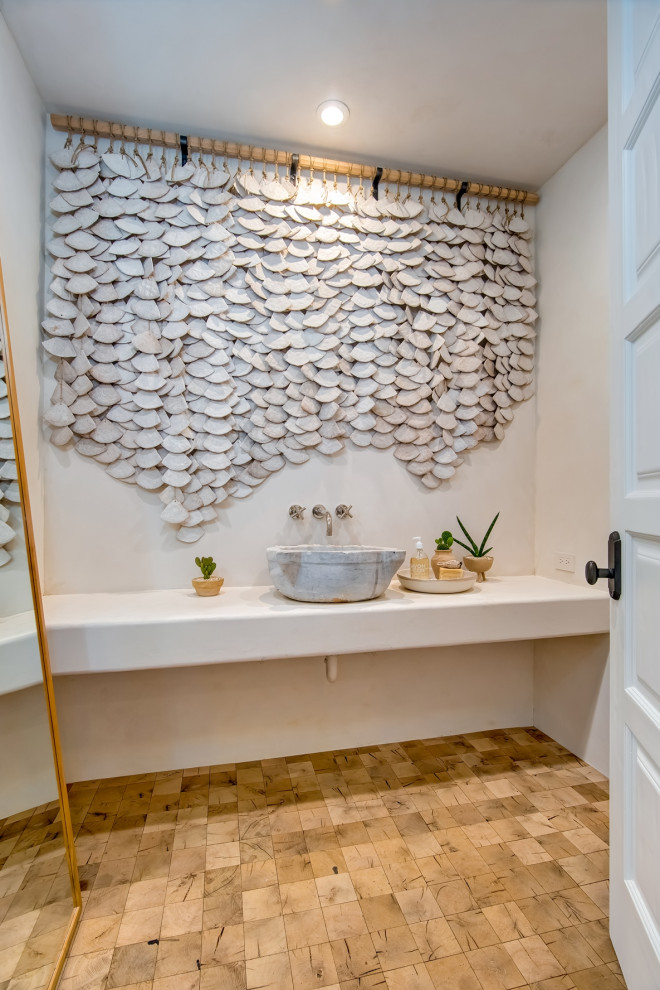 На фото: туалет в средиземноморском стиле с белыми стенами, настольной раковиной, коричневым полом и белой столешницей с