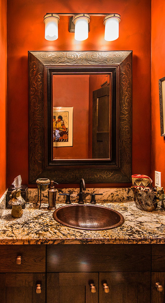 Cette photo montre un petit WC et toilettes chic en bois foncé avec un lavabo posé, un placard avec porte à panneau encastré, un plan de toilette en granite et un mur orange.
