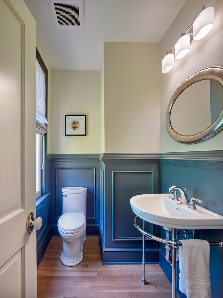 Inspiration for a small classic cloakroom in New York with a one-piece toilet, beige walls, medium hardwood flooring, a console sink and brown floors.