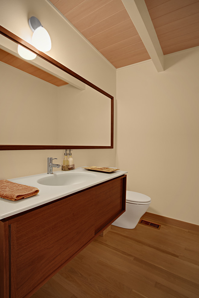 Retro Gästetoilette mit integriertem Waschbecken, flächenbündigen Schrankfronten, hellbraunen Holzschränken und weißer Waschtischplatte in Seattle