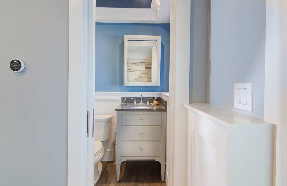 Design ideas for a small modern cloakroom in Other with flat-panel cabinets, grey cabinets, a two-piece toilet, blue walls, porcelain flooring, a submerged sink, engineered stone worktops, brown floors, black worktops, a freestanding vanity unit and wainscoting.