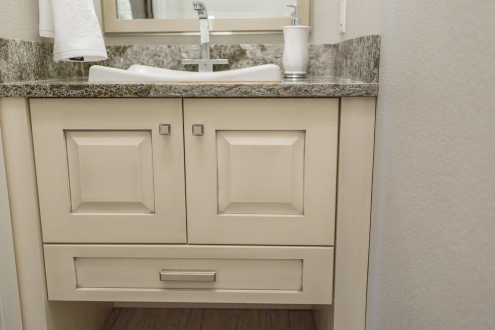 Aménagement d'un WC et toilettes classique avec un placard avec porte à panneau surélevé, des portes de placard beiges, un mur blanc et un plan de toilette en granite.