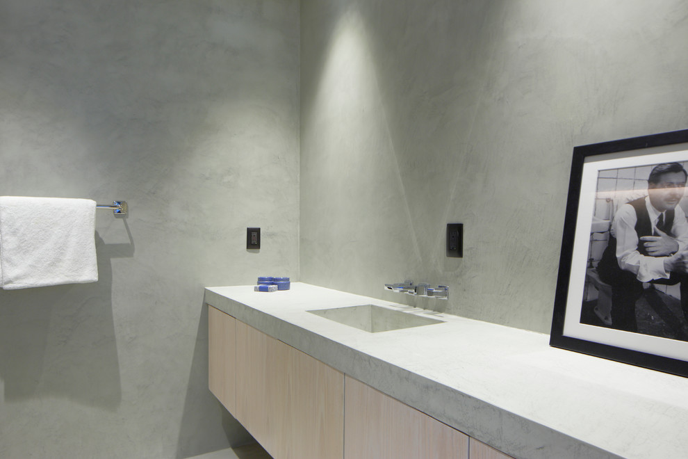 Idée de décoration pour un WC et toilettes design en bois clair de taille moyenne avec un placard à porte plane, un mur gris, un plan de toilette en béton et un plan de toilette gris.