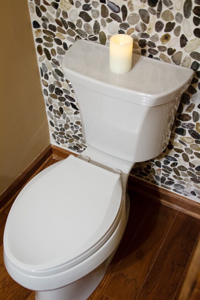 Immagine di un piccolo bagno di servizio minimalista con lavabo a bacinella, ante lisce, ante in legno scuro, top in marmo, WC monopezzo, piastrelle multicolore, pareti beige e piastrelle di ciottoli