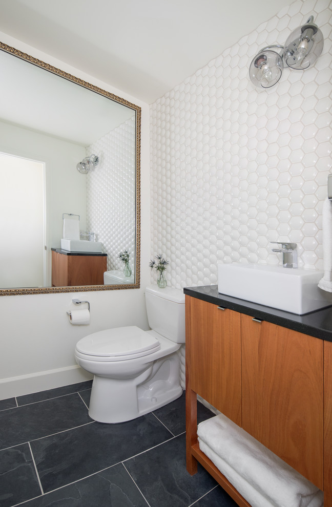 Powder room - 1960s white tile and ceramic tile slate floor and black floor powder room idea in Denver with furniture-like cabinets, medium tone wood cabinets, a two-piece toilet, white walls, an undermount sink and black countertops