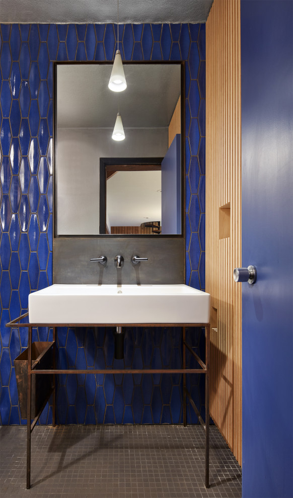 Exemple d'un petit WC et toilettes rétro avec WC à poser, un carrelage bleu, des carreaux de céramique, un mur bleu, un sol en carrelage de céramique, un lavabo de ferme et un sol noir.