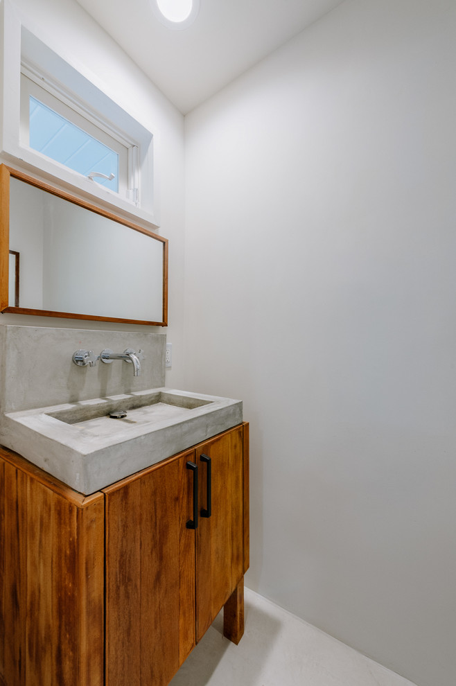 Modelo de aseo vintage pequeño con armarios con paneles lisos, paredes blancas, lavabo integrado y encimera de cemento