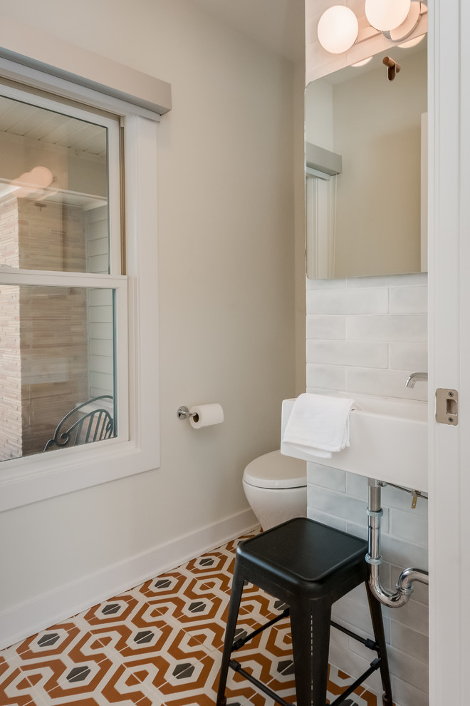Kleine Retro Gästetoilette mit Toilette mit Aufsatzspülkasten, weißen Fliesen, Keramikfliesen, grauer Wandfarbe, Keramikboden, Wandwaschbecken und buntem Boden in New York