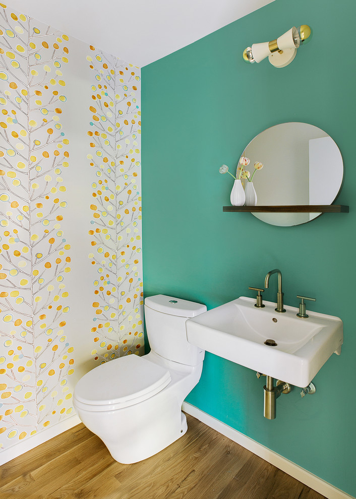 Cette image montre un petit WC et toilettes design avec WC séparés, un lavabo suspendu, parquet clair et un mur vert.