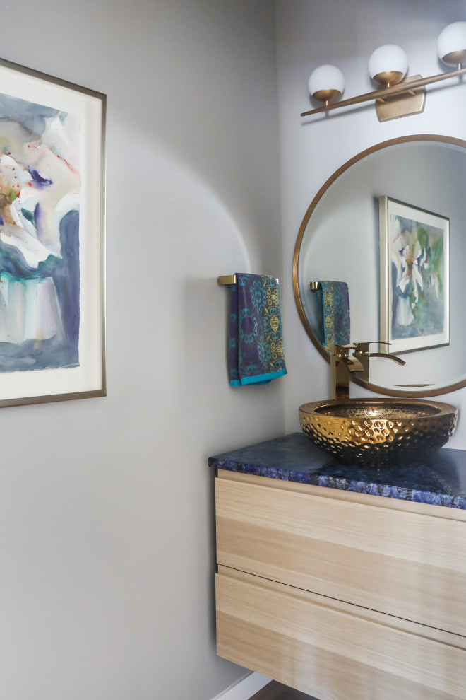 Inredning av ett modernt litet blå blått toalett, med släta luckor, skåp i ljust trä, en toalettstol med separat cisternkåpa, grå väggar, ljust trägolv, ett fristående handfat, granitbänkskiva och brunt golv