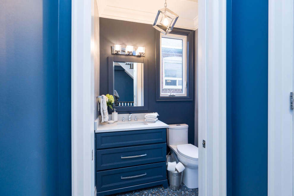 Cette photo montre un WC et toilettes chic avec un placard à porte shaker, des portes de placard bleues, WC à poser, un mur bleu, un sol en carrelage de porcelaine, un lavabo encastré, un plan de toilette en quartz modifié, un sol multicolore, un plan de toilette blanc et meuble-lavabo sur pied.