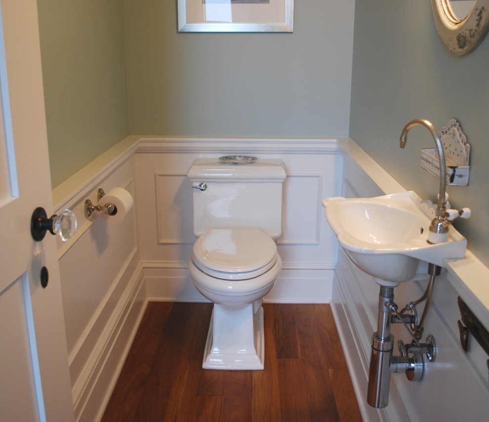 Inredning av ett maritimt litet toalett, med ett väggmonterat handfat, gröna väggar och en toalettstol med hel cisternkåpa