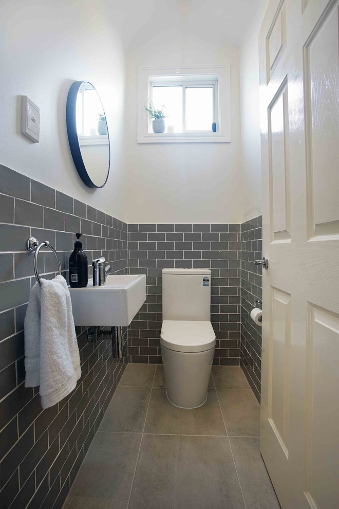 Пример оригинального дизайна: туалет в стиле неоклассика (современная классика) с раздельным унитазом, серой плиткой, плиткой кабанчик, белыми стенами, подвесной раковиной и серым полом