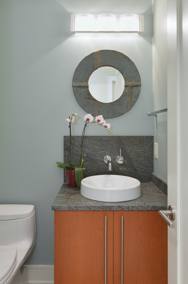 Idee per un piccolo bagno di servizio design con ante lisce, ante in legno scuro, WC monopezzo, pareti blu, lavabo a bacinella e top multicolore