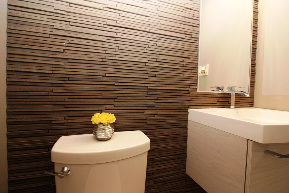 Modern inredning av ett mellanstort vit vitt toalett, med släta luckor, grå skåp, en toalettstol med hel cisternkåpa, bruna väggar och ett integrerad handfat