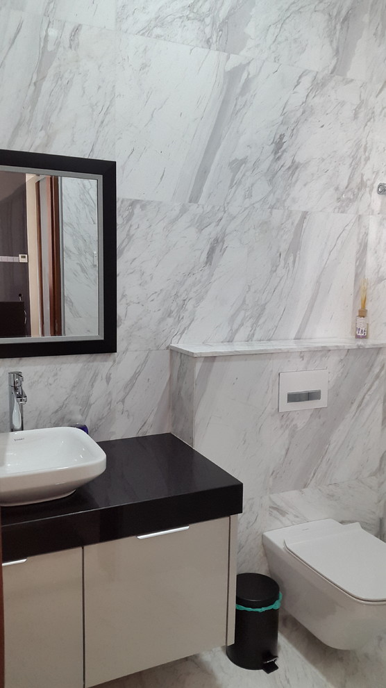 This is an example of a small modern cloakroom in Other with a wall mounted toilet, marble flooring, a vessel sink and engineered stone worktops.