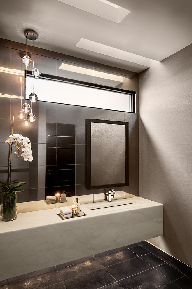 Пример оригинального дизайна: туалет в современном стиле с монолитной раковиной, черной плиткой и серыми стенами