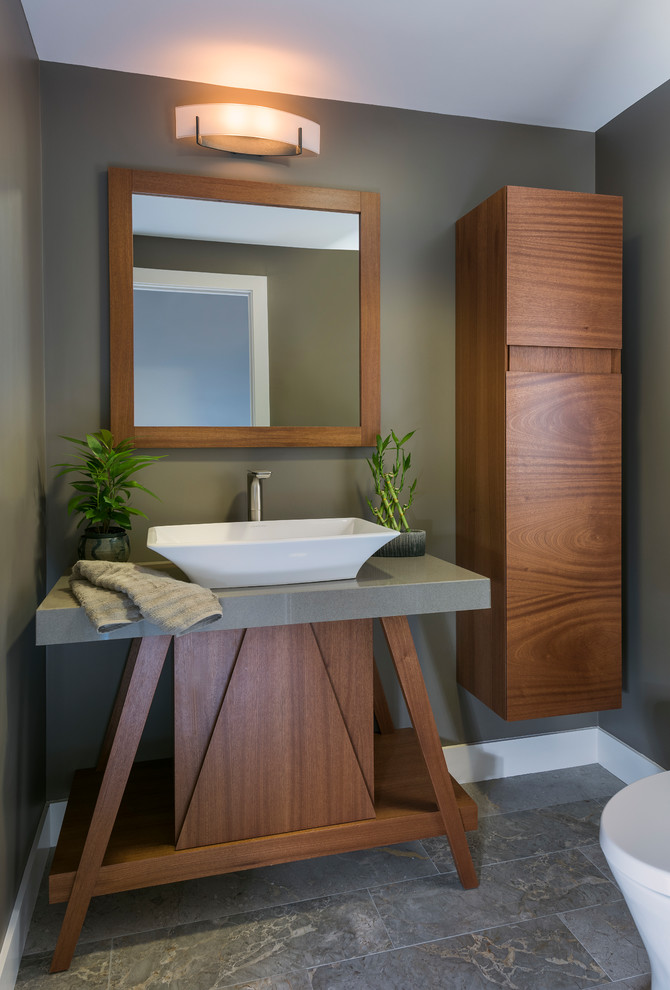 Cette image montre un petit WC et toilettes asiatique en bois foncé avec un placard à porte plane, WC à poser, un mur gris, un sol en ardoise, une vasque, un plan de toilette en calcaire, un sol gris et un plan de toilette gris.