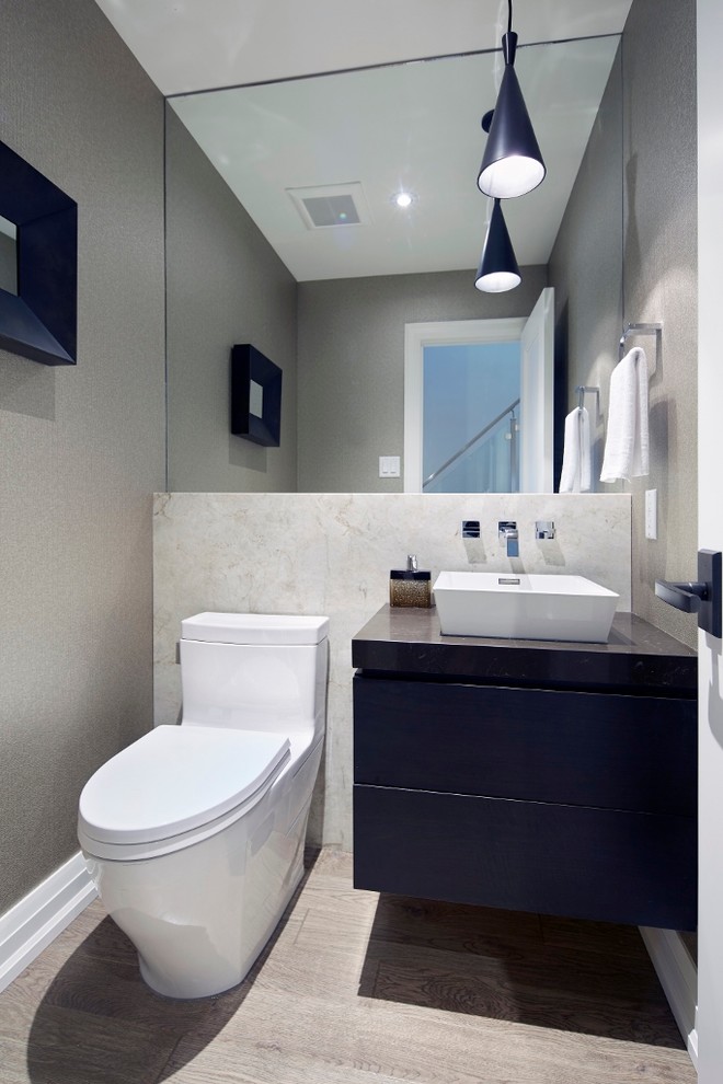 Kleine Moderne Gästetoilette mit flächenbündigen Schrankfronten, Toilette mit Aufsatzspülkasten, beigen Fliesen, Steinplatten, grauer Wandfarbe, Aufsatzwaschbecken, Mineralwerkstoff-Waschtisch, hellem Holzboden und blauen Schränken in Toronto