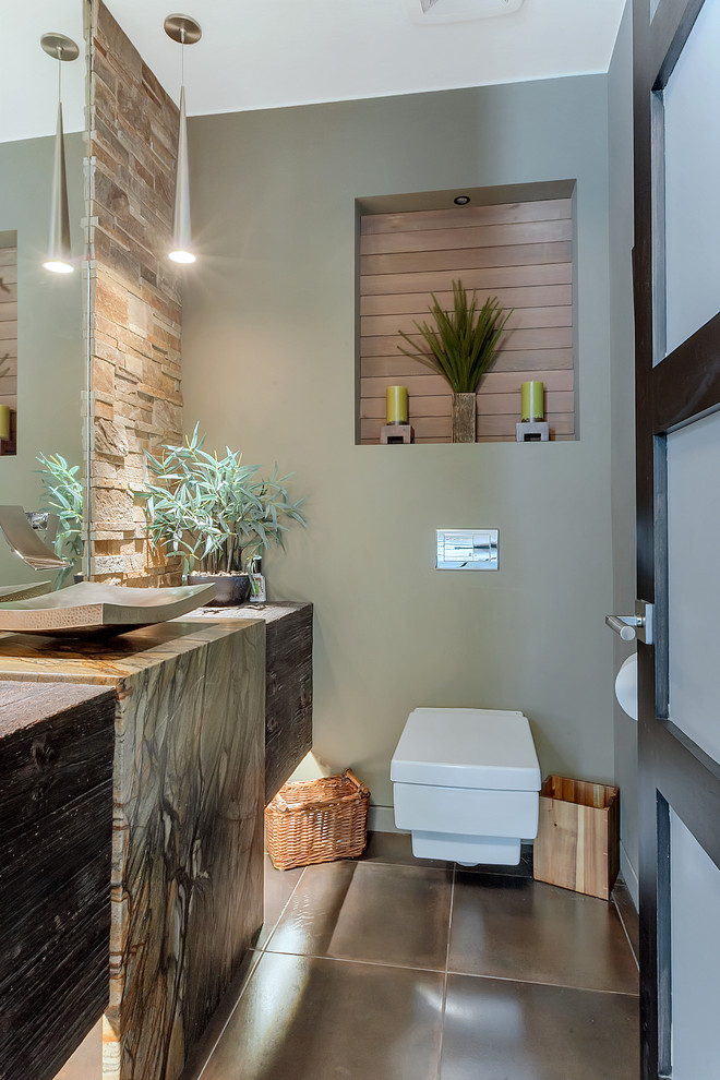 Photo of a small contemporary cloakroom in Minneapolis with a wall mounted toilet, stone tiles, ceramic flooring, a vessel sink, granite worktops, brown floors, beige tiles, green walls and flat-panel cabinets.