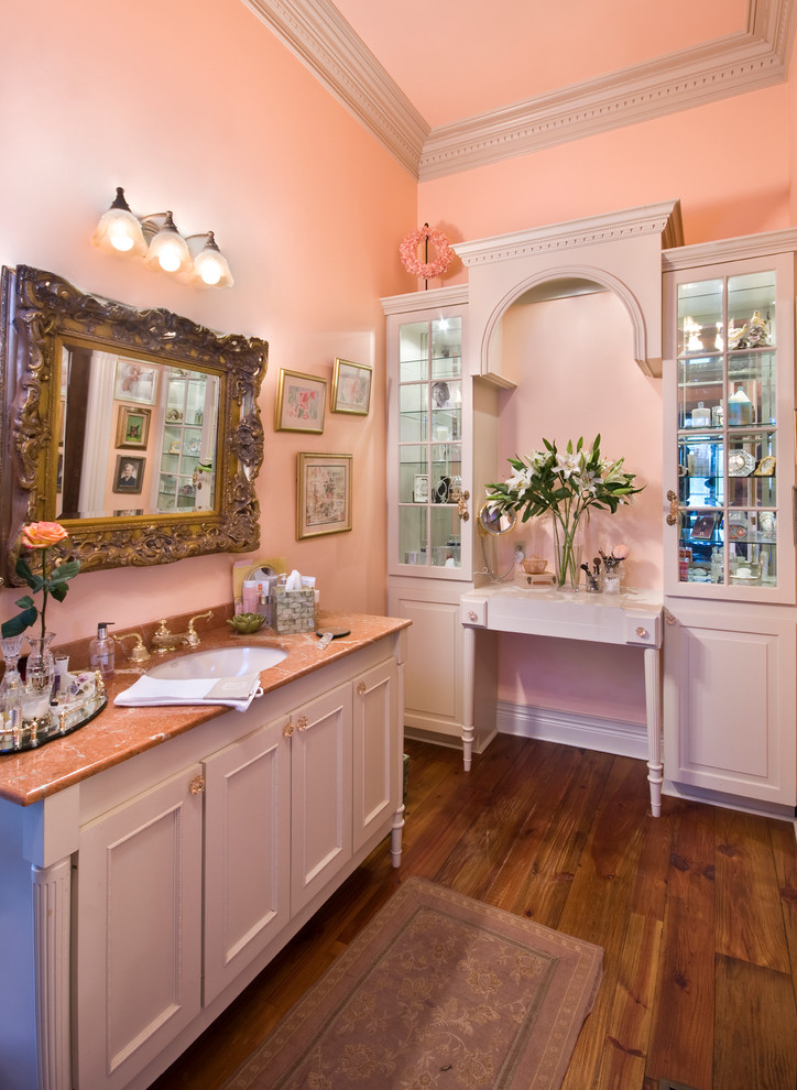 Idee per un grande bagno di servizio chic con lavabo sottopiano, consolle stile comò, ante bianche, top in granito, pareti rosa e pavimento in legno massello medio