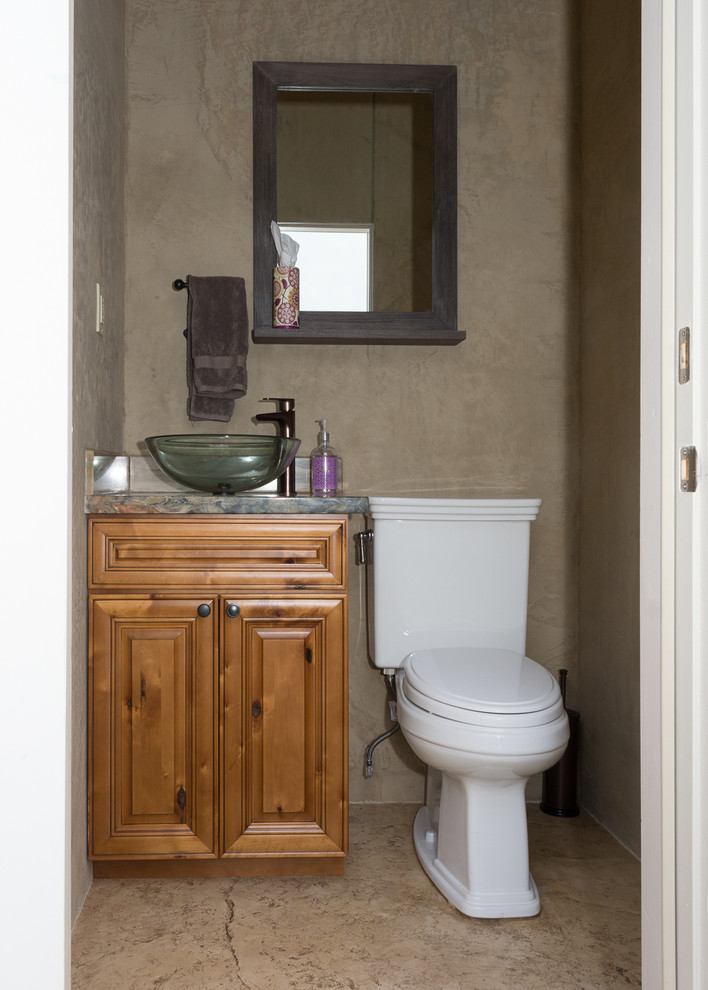 Aménagement d'un petit WC et toilettes classique en bois brun avec un placard avec porte à panneau surélevé, WC à poser, un mur marron, un sol en travertin, une vasque, un plan de toilette en granite et un sol marron.