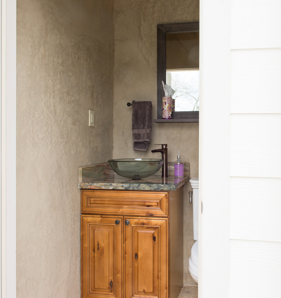 Cette image montre un petit WC et toilettes traditionnel en bois brun avec un placard avec porte à panneau surélevé, WC à poser, un mur marron, un sol en travertin, une vasque, un plan de toilette en granite et un sol marron.