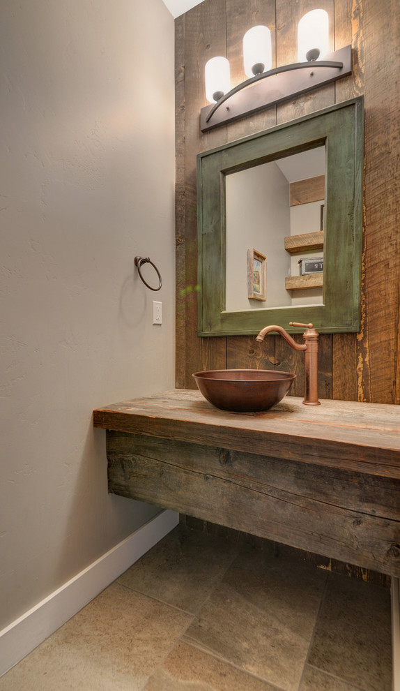 アルバカーキにあるラスティックスタイルのおしゃれなトイレ・洗面所 (一体型トイレ	、グレーの壁、磁器タイルの床、ベッセル式洗面器、木製洗面台、ブラウンの洗面カウンター) の写真