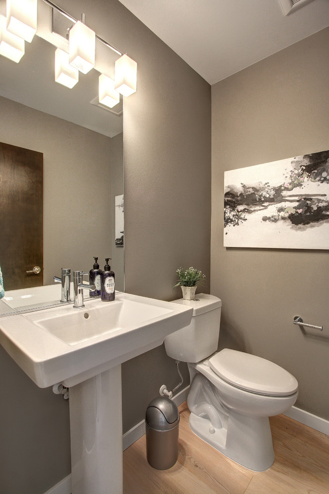 Esempio di un bagno di servizio minimalista con lavabo a colonna, WC a due pezzi, pareti grigie e parquet chiaro