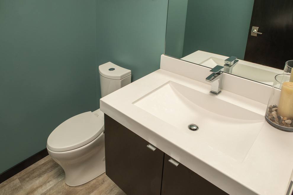 Photo of a small modern cloakroom in Milwaukee with flat-panel cabinets, brown cabinets, a two-piece toilet, blue walls, light hardwood flooring, an integrated sink, quartz worktops, beige worktops and a floating vanity unit.