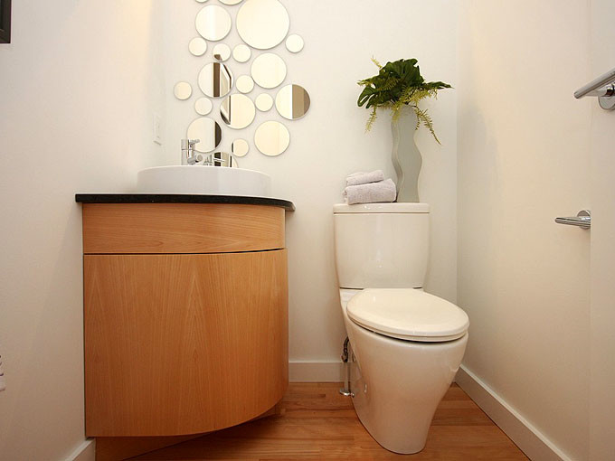 Cette image montre un petit WC et toilettes design en bois clair avec une vasque, un placard à porte plane, WC séparés, un mur blanc et parquet clair.