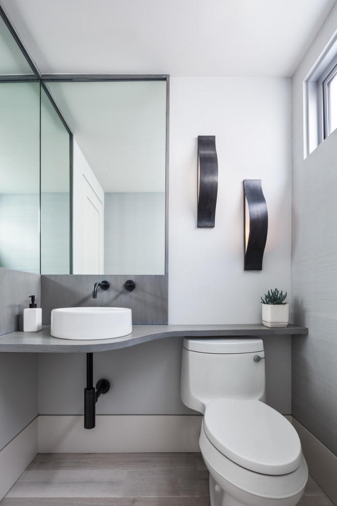 Immagine di un bagno di servizio design con WC monopezzo, pareti bianche, lavabo a bacinella, pavimento grigio e top grigio