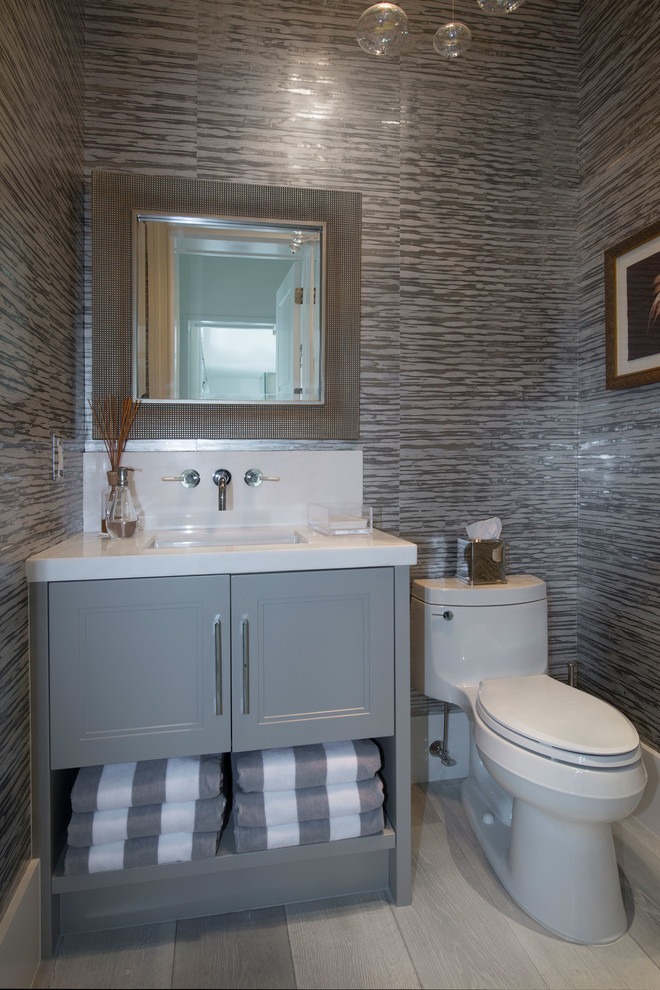 Aménagement d'un WC et toilettes bord de mer avec des portes de placard grises, WC à poser et un placard avec porte à panneau encastré.