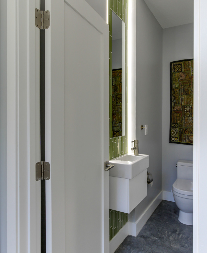 Réalisation d'un petit WC et toilettes minimaliste avec un placard à porte plane, des portes de placard blanches, WC à poser, un carrelage vert, un mur gris, sol en béton ciré, un lavabo suspendu et un carrelage en pâte de verre.