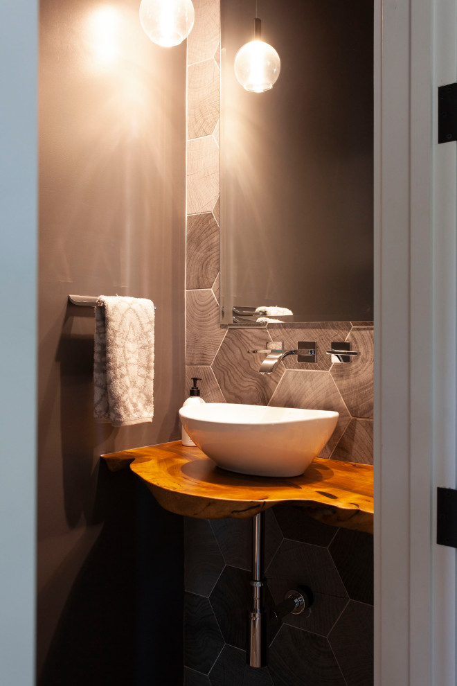 This is an example of a small contemporary cloakroom in San Francisco with a wall mounted toilet, grey tiles, ceramic tiles, grey walls, a vessel sink, wooden worktops, brown worktops and a floating vanity unit.