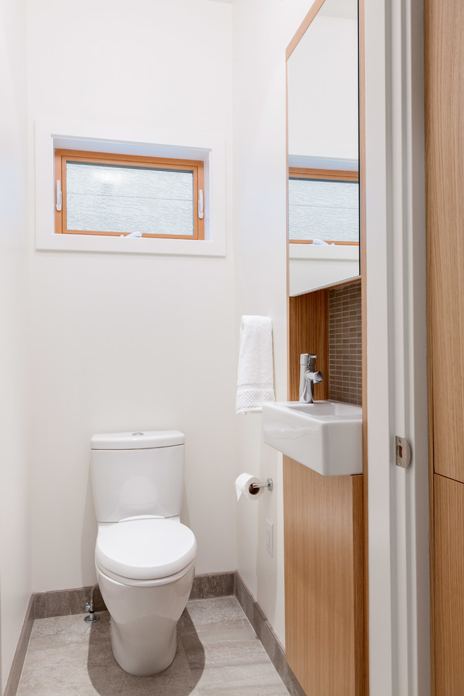 Inspiration for a small modern cloakroom in Vancouver with a wall-mounted sink, flat-panel cabinets, medium wood cabinets, brown tiles, grey tiles, ceramic tiles, white walls, ceramic flooring and a two-piece toilet.