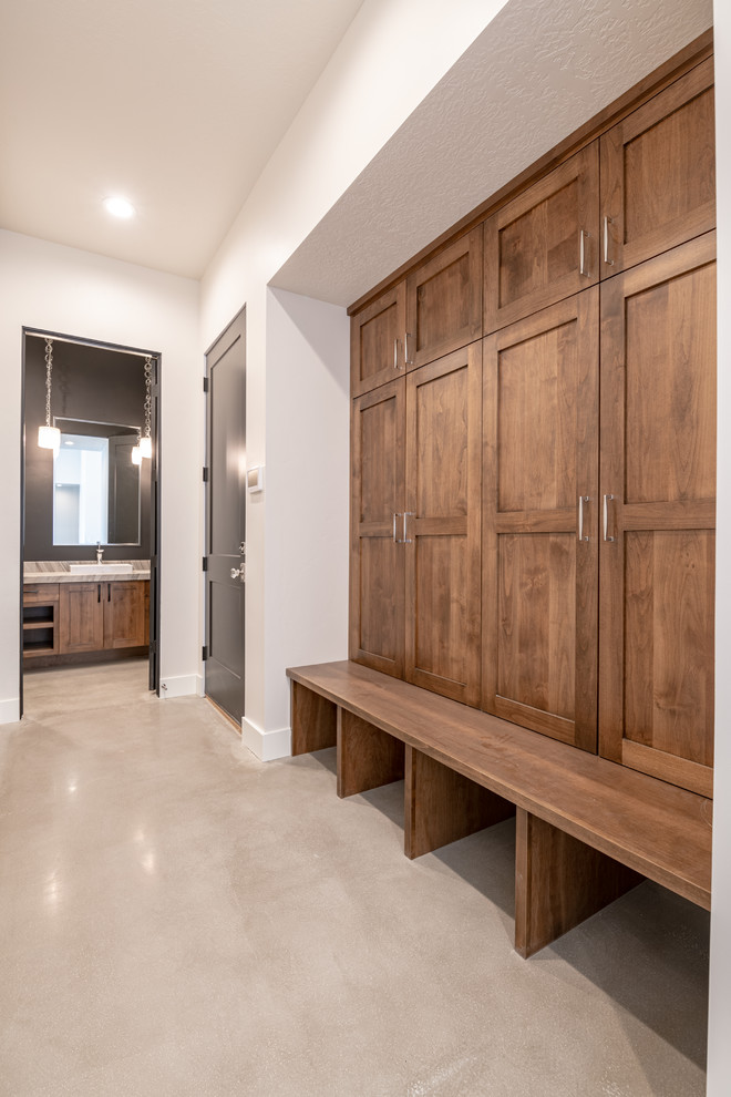 Design ideas for a large country cloakroom in Salt Lake City with flat-panel cabinets, medium wood cabinets, a two-piece toilet, black tiles, stone slabs, black walls, concrete flooring, a vessel sink, quartz worktops, grey floors and beige worktops.