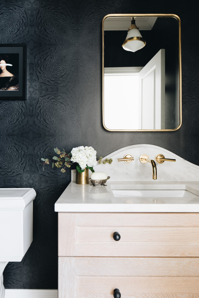 Small classic cloakroom in Chicago with shaker cabinets, light wood cabinets, a two-piece toilet, black walls, light hardwood flooring, a submerged sink, marble worktops, brown floors, white worktops, a freestanding vanity unit and wallpapered walls.