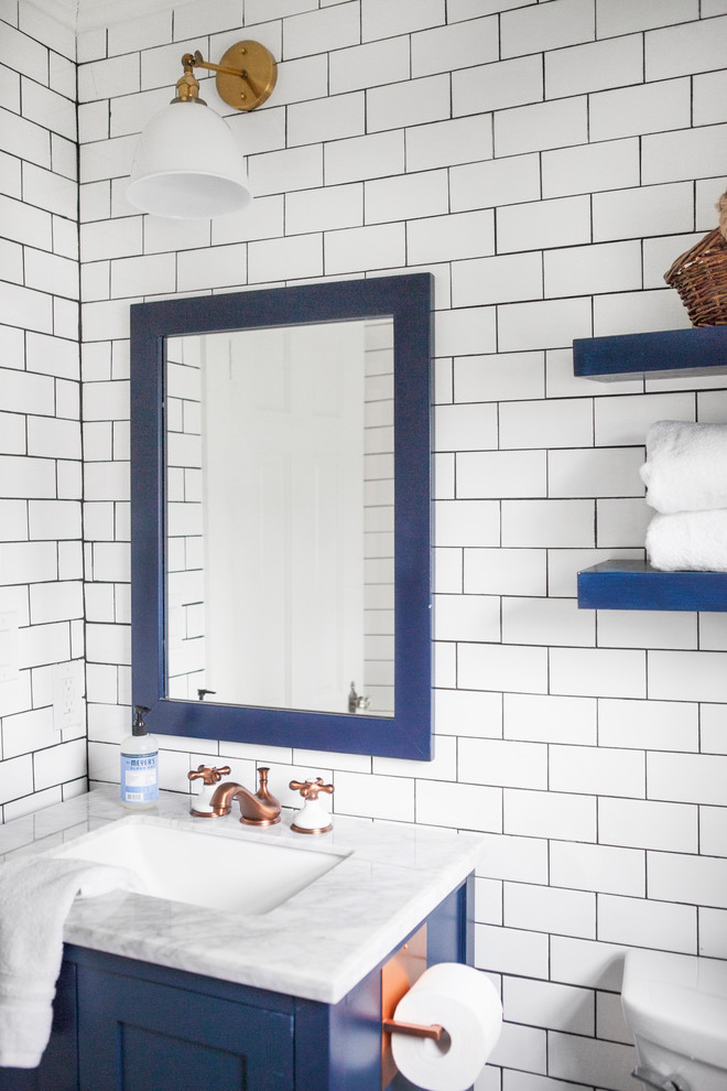 Cette image montre un WC et toilettes rustique de taille moyenne avec un placard à porte shaker, des portes de placard bleues, WC séparés, un carrelage blanc, un carrelage métro, un mur blanc, un lavabo encastré et un plan de toilette blanc.