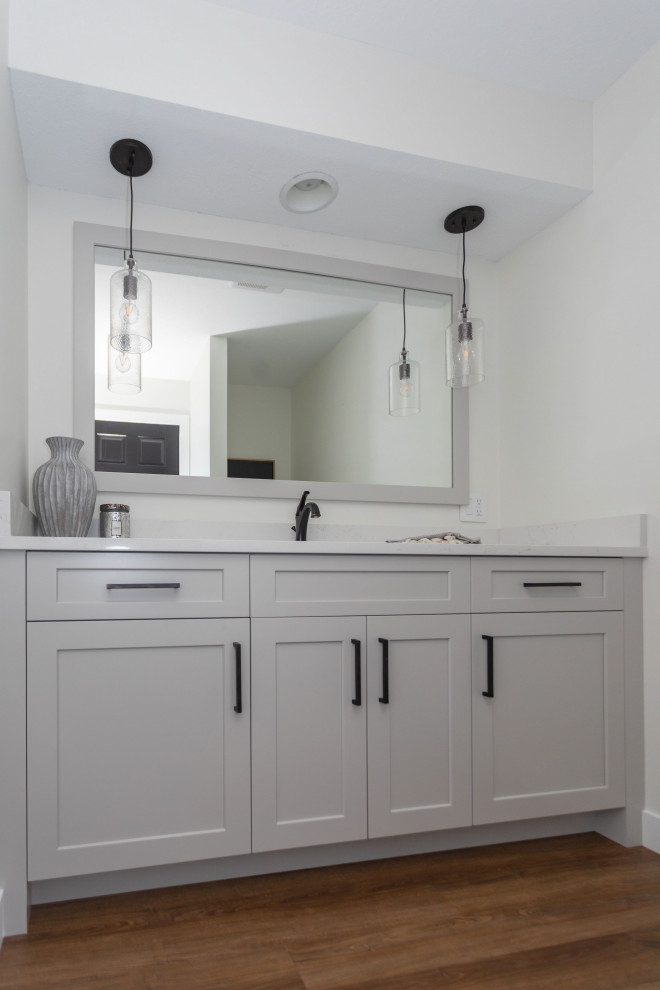 Inspiration for a small cottage medium tone wood floor, brown floor and vaulted ceiling powder room remodel in Minneapolis with flat-panel cabinets, gray cabinets, white walls, white countertops and a built-in vanity