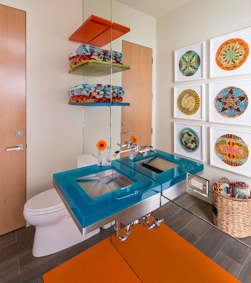 Photo of a medium sized retro cloakroom in Austin with open cabinets, a one-piece toilet, beige walls, porcelain flooring, an integrated sink, glass worktops and blue worktops.