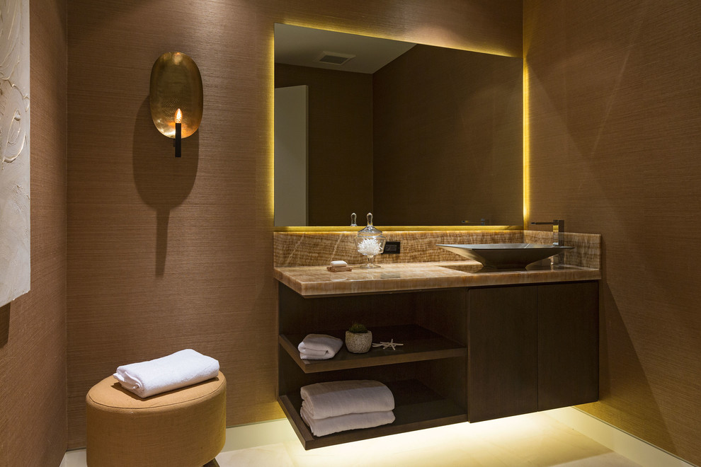 Foto på ett mellanstort funkis toalett, med släta luckor, skåp i mörkt trä, brun kakel, klinkergolv i porslin, ett fristående handfat, marmorbänkskiva och bruna väggar
