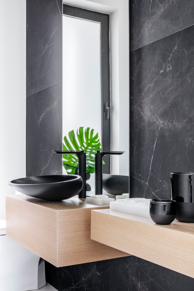 Inspiration for a medium sized modern cloakroom in Miami with a one-piece toilet, black tiles, white walls, marble flooring, a vessel sink, wooden worktops, white floors and beige worktops.