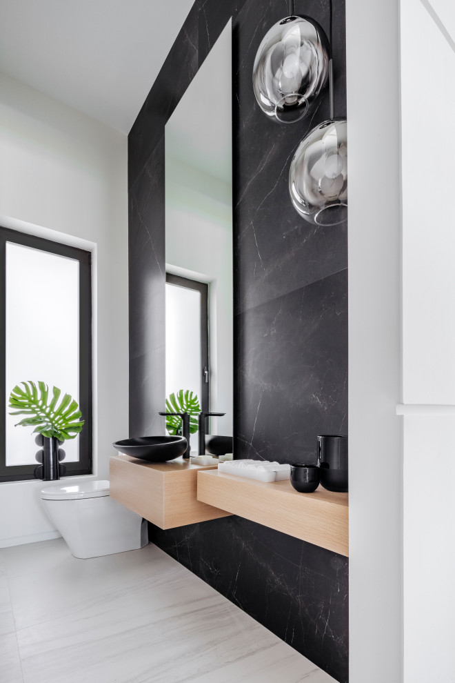 Mittelgroße Moderne Gästetoilette mit Toilette mit Aufsatzspülkasten, schwarzen Fliesen, weißer Wandfarbe, Marmorboden, Aufsatzwaschbecken, Waschtisch aus Holz, weißem Boden und beiger Waschtischplatte in Miami