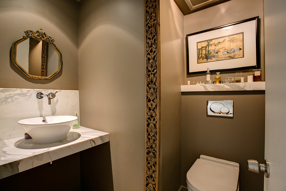 Idée de décoration pour un petit WC et toilettes minimaliste avec WC à poser, un mur beige, une vasque, un plan de toilette en marbre et un carrelage blanc.