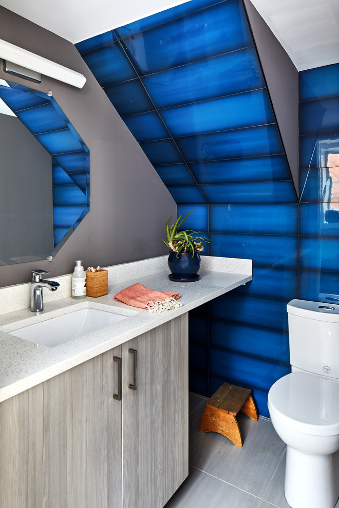 Aménagement d'un petit WC et toilettes moderne avec un placard à porte plane, WC séparés, un carrelage bleu, un mur gris, un sol en carrelage de porcelaine, un lavabo encastré, un plan de toilette en quartz modifié, un sol gris et un plan de toilette blanc.