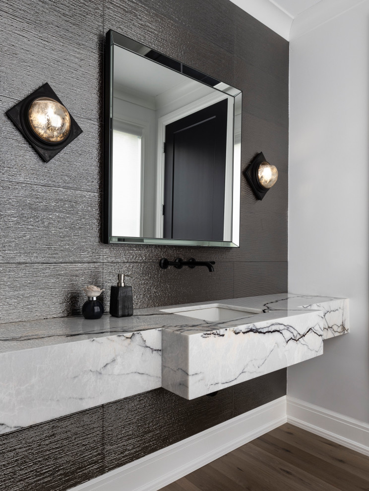 Inspiration for a large contemporary cloakroom in Detroit with white cabinets, a one-piece toilet, grey tiles, porcelain tiles, grey walls, light hardwood flooring, a submerged sink, marble worktops, brown floors, white worktops, a floating vanity unit and a feature wall.